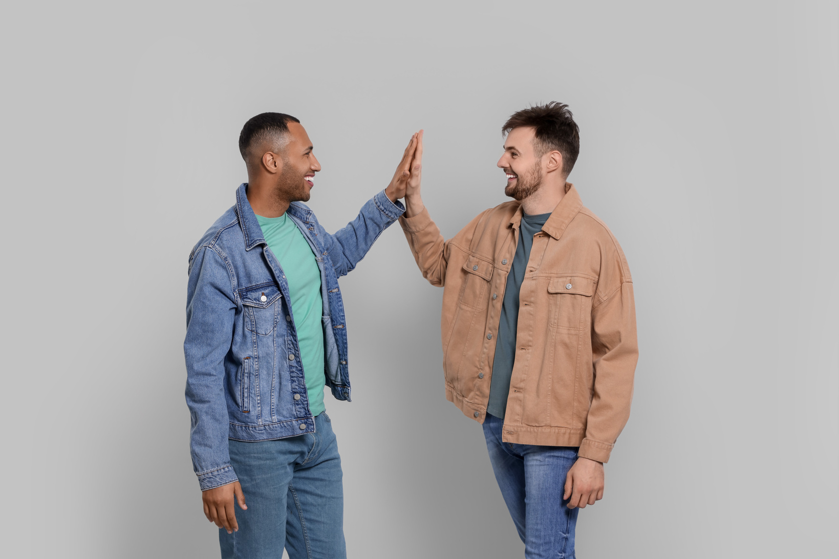 Men Giving High Five on Grey Background